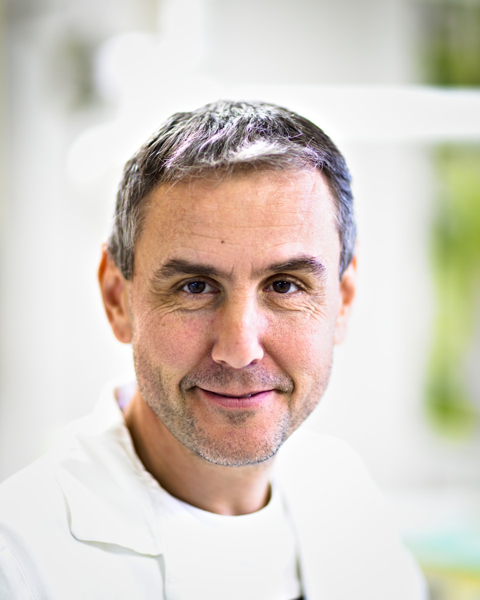 A man in a white lab coat smiles at the camera